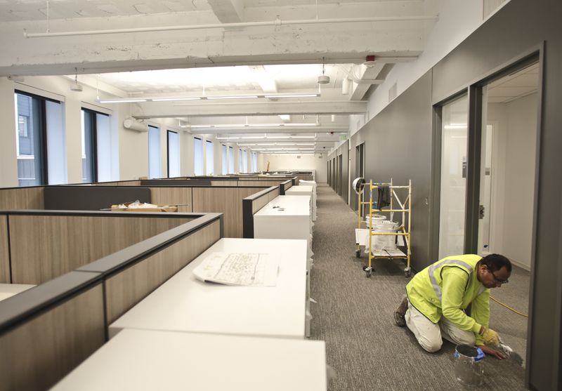 Painter Carlos Palacios touches up window and door frames as renovation work is nearing completion on a lower floor of the State Office Building. Offices on upper floors are already occupied.